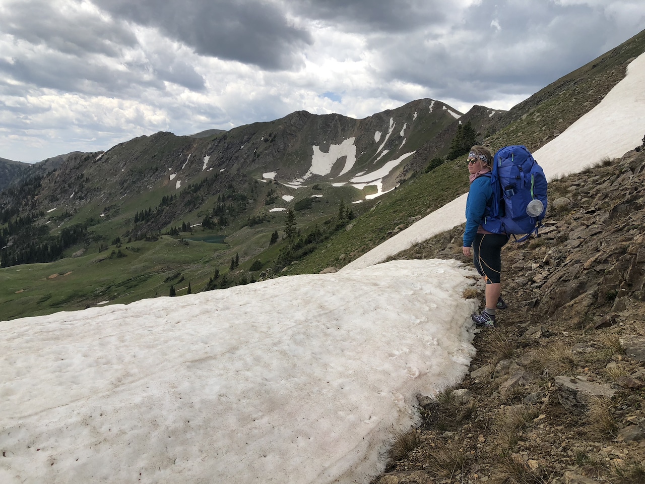 Marie taking in the views from atop a mountain, standing just next to a pile perma-frost snow.